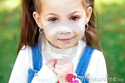 Sweet little girl outdoors with curly hair in two long tails, closeup portret. Stock Photo