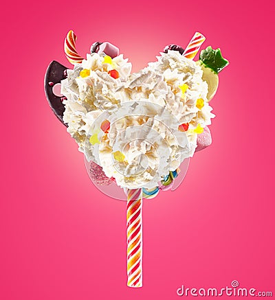 Sweet Lolipop in Heart form of whipped cream with sweets, jellies, heart front view. Crazy freakshake food trend. Front Stock Photo