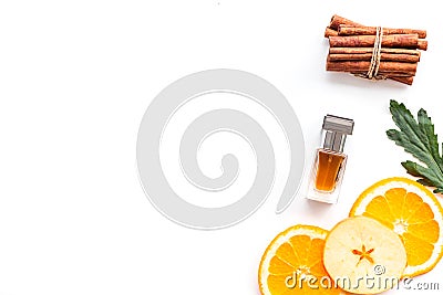 Sweet perfume with fruit fragrance. Bottle of perfume near apple, orange, cinnamon on white background top view cop Stock Photo