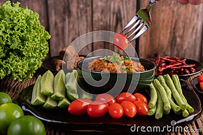 Sweet pork in a black bowl, complete with cucumbers, long beans, tomatoes, and side dishes Stock Photo