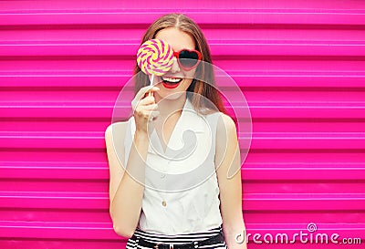 Sweet pretty young woman having fun with lollipop over pink Stock Photo