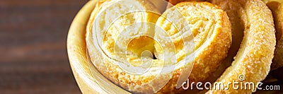 Sweet pretzels made of puff pastry in a bowl on a wooden table. Banner Stock Photo