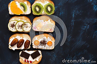 Sweet sandwiches with cream cheese and fruit-kiwi, orange, physalis, pineapple, pear, chocolate, dates. Blue dark background, top Stock Photo