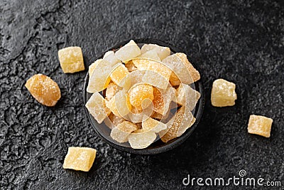 Sweet and spicy candied ginger in black bowl on dark stone background Stock Photo