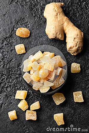 Sweet and spicy candied ginger in black bowl on dark stone background. Top view Stock Photo