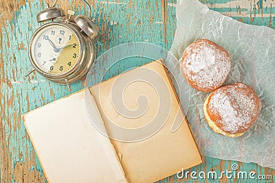 Sweet sugary donuts, book and vintage clock on rustic table Stock Photo