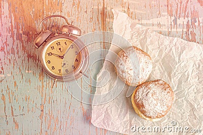 Sweet sugary donuts and vintage clock on rustic table Stock Photo