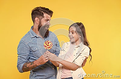 Sweet surprise. Bearded man give lollipop to surprised child. Sweet tooth family yellow background. Sweetshop and Stock Photo