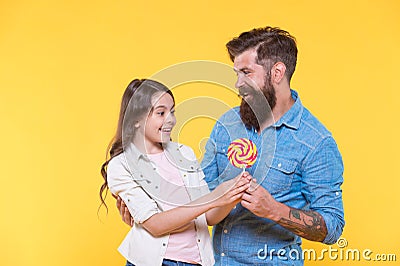 Sweet surprise. Bearded man give lollipop to surprised child. Sweet tooth family yellow background. Sweetshop and Stock Photo