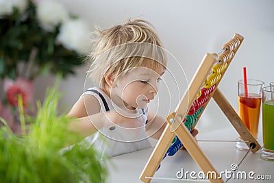 Sweet toddler child, blond boy, learning math at home with colorful abacus Stock Photo