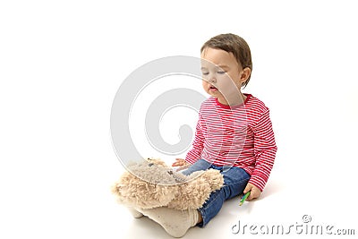 Sweet toddler girl playing with her teddy bear putting him on feet to sleep Stock Photo