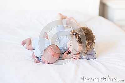 Sweet toddler girl supporting her newborn brother Stock Photo