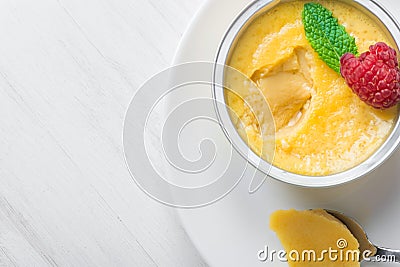 Sweet vanilla egg custard cream flan with caramel syrup fresh raspberry mint on white plate. Golden sugar crust Stock Photo