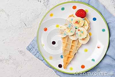 Sweet waffle with banana and strawberry in a shape of ice cream cone, meal for kids idea, top view Stock Photo