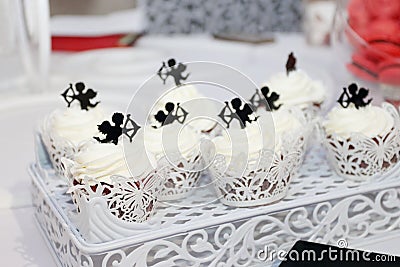 Sweet white cupcakes with small cupids are on table during celeb Editorial Stock Photo