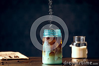 Sweetener Pouring Into Iced Organic Coffee Served In Blue Mason Jar Stock Photo