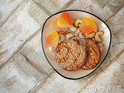 Sweets and nuts on a small rectangular plate, oatmeal cookies and heart-shaped marmalade Stock Photo