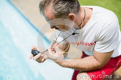 Swim coach looking at stop watch near poolside Stock Photo