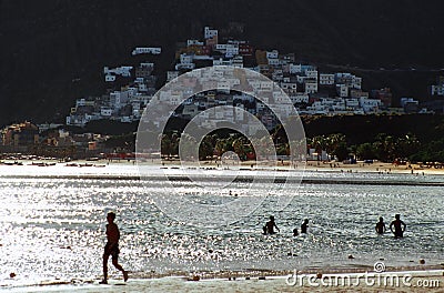 Swimming at a beach and the small colorful village of San Andres, Spain in the background Editorial Stock Photo