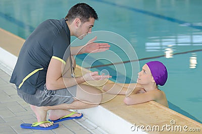 Swimming coach by pool talking to swimmer Stock Photo