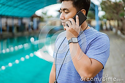 a swimming coach wearing a stopwatch makes a phone call using a mobile phone Stock Photo