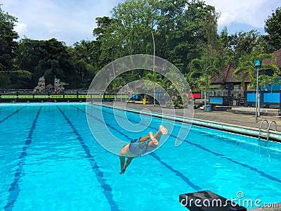 Swimming man jumps into swimming pool water. Water sport concept image. Editorial Stock Photo