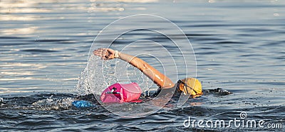 Swimming in the open water with pink flotation device for safety Editorial Stock Photo