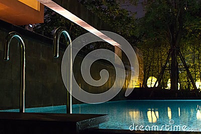 Swimming pool area at night with soft glowing outdoor lighting in expensive home in tropical southeast asia with flat water and ro Stock Photo