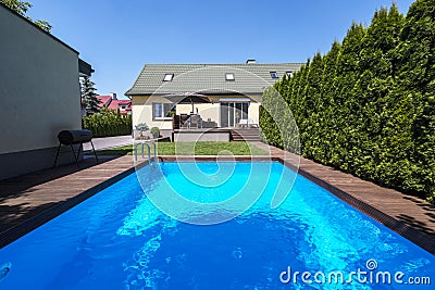 Swimming pool in the garden of house with trees during summer. R Stock Photo