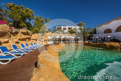 Swimming pool and luxury buildings behind it, palm trees, loungers Stock Photo