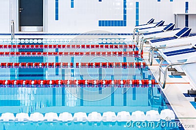 Swimming pool with marked red and white lanes. Empty swimming pool without people with quiet standing water. Stock Photo