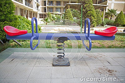 Swing on a metal spiral.Double seats rocking spring . New modern plastic bright colorful blue and red empty toy seesaw swing on Stock Photo