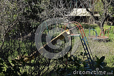 Swings and slides in abandoned overgrown playground Stock Photo