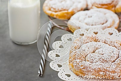 Swirl Danish Pastry Powdered on Cooling Rack and Cake Stand. Bottle of Milk Striped Straw. Stock Photo