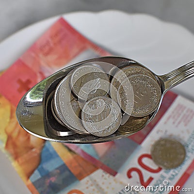 Swiss rappen in a tablespoon and paper bills Stock Photo
