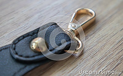 Swivel carabiner fastener with leather black bag strap on a wooden background. Metal carabiner with swivel clip or hook. Small Stock Photo