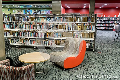 At the community public local library. Chairs waiting for readers and bookshelfs full of books. Editorial Stock Photo
