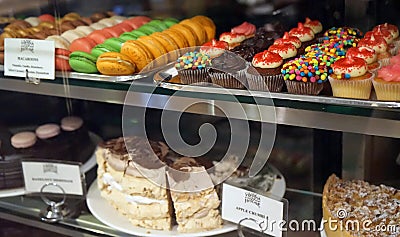 Pastry shop window display with variety of cupcakes, muffins, macaroons, cakes Editorial Stock Photo