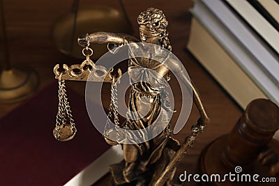 Symbol of fair treatment under law. Figure of Lady Justice, books and gavel on wooden table, closeup Stock Photo