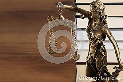 Symbol of fair treatment under law. Figure of Lady Justice and books on wooden table, closeup with space for text Stock Photo