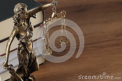 Symbol of fair treatment under law. Figure of Lady Justice and books on wooden table, closeup with space for text Stock Photo