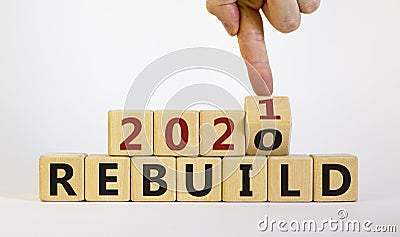 Symbol of 2021 rebuild. Male hand flips wooden cubes and changes the inscription `Rebuild 2020` to `Rebuild 2021`. Beautiful w Stock Photo