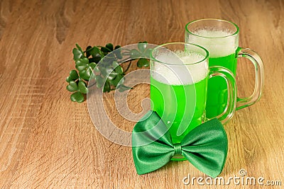 Symbols of celebrating Saint Patrick Day. Green bow tie, beer and leaves of shamrock on the wooden background. Traditional irish Stock Photo