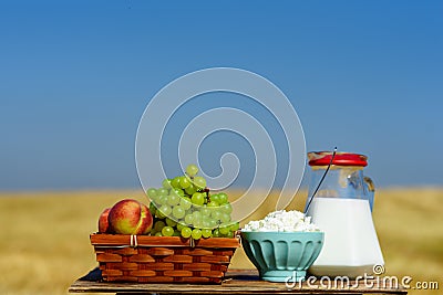 Symbols of jewish holiday - Shavuot.First fruits habikkurim in hebrew, white cheese and milk on wooden table. Stock Photo