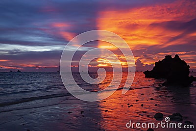 Symmetric sunset on the shore with reflection in sea water Stock Photo