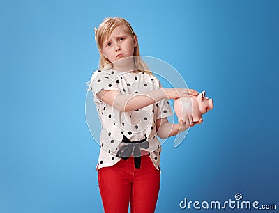 Sympathetic modern girl fondle piggy bank with plaster on blue Stock Photo