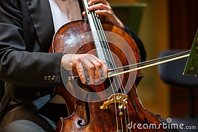 Symphonic orchestra performing on stage and playing a classical music concert, cellist in the foreground Stock Photo