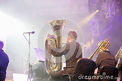 Symphony orchestra on the stage, orchestral brass section, behind the scenes shoot.Tubaist in black shirt blow in big brass tube Editorial Stock Photo