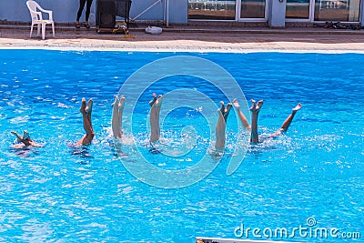 Synchronised swimming. Beautiful lean female legs in the water of a swimming pool. Concept of beauty, artistry Stock Photo