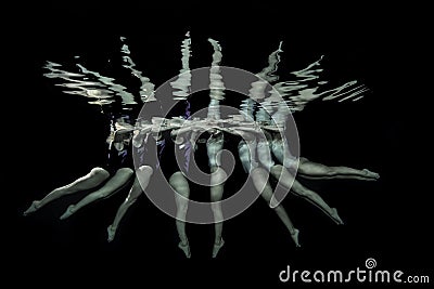 Synchronized swimmers take a pose underwater in a pool Stock Photo